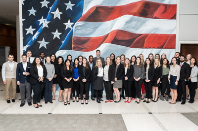 Bush Board Fellows - photo of Bush School students in front of a wall with the USA flag on it
