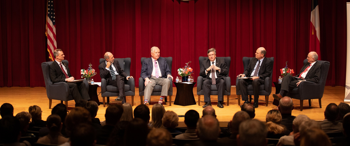 A roundtable discussion on stage including six men