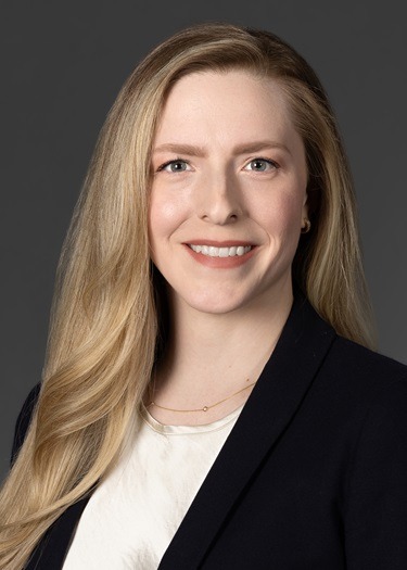 A head-and-shoulders, professional portrait photo of a smiling Kelsey McKechnie in a sportcoat and white jacket.