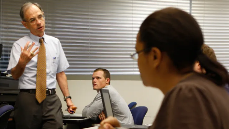 faculty member teaching and interacting with students in a classroom setting.